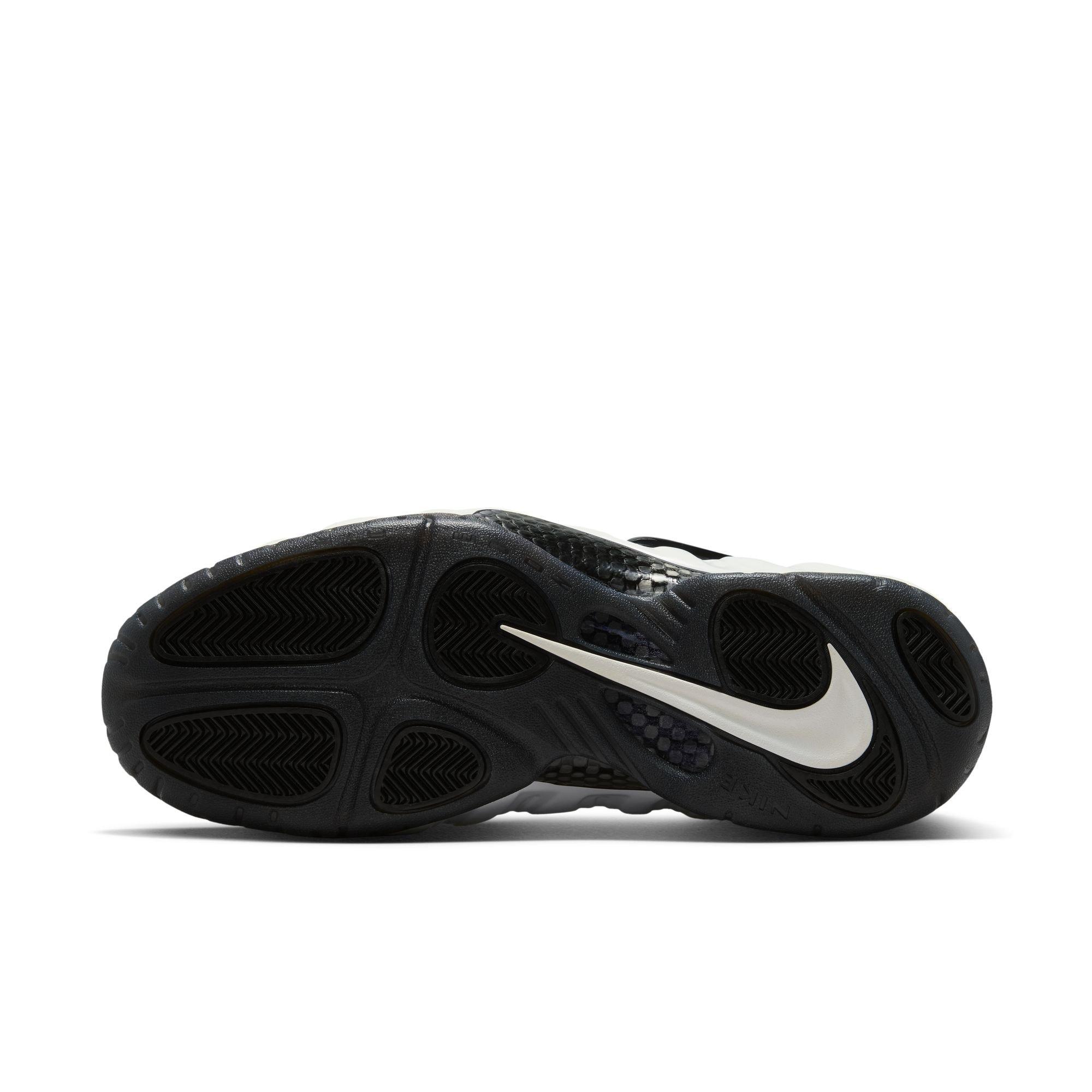 Bottom view of the Nike Air Foamposite Pro Premium sneaker showing black traction pods, carbon-fiber details and a large white Nike Swoosh.