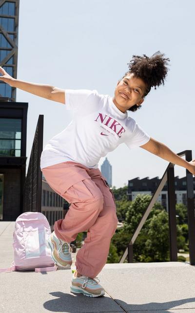 Girl wearing a white and pink Nike tee and colorful Air Max 97 sneakers