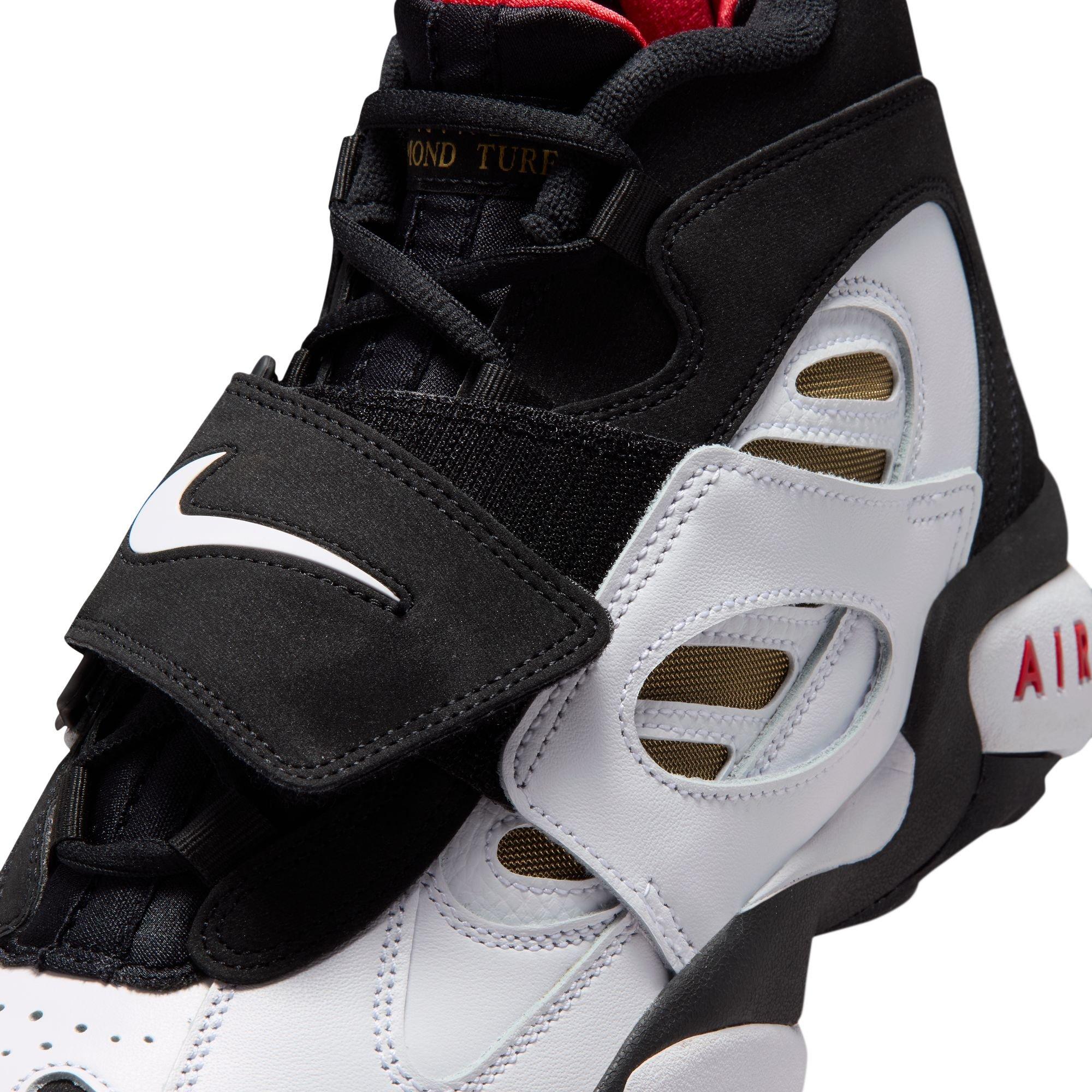 Close-up of the Nike Air Diamond Turf II featuring black laces, a black midfoot strap with a white Nike Swoosh, white leather overlays and gold mesh details.