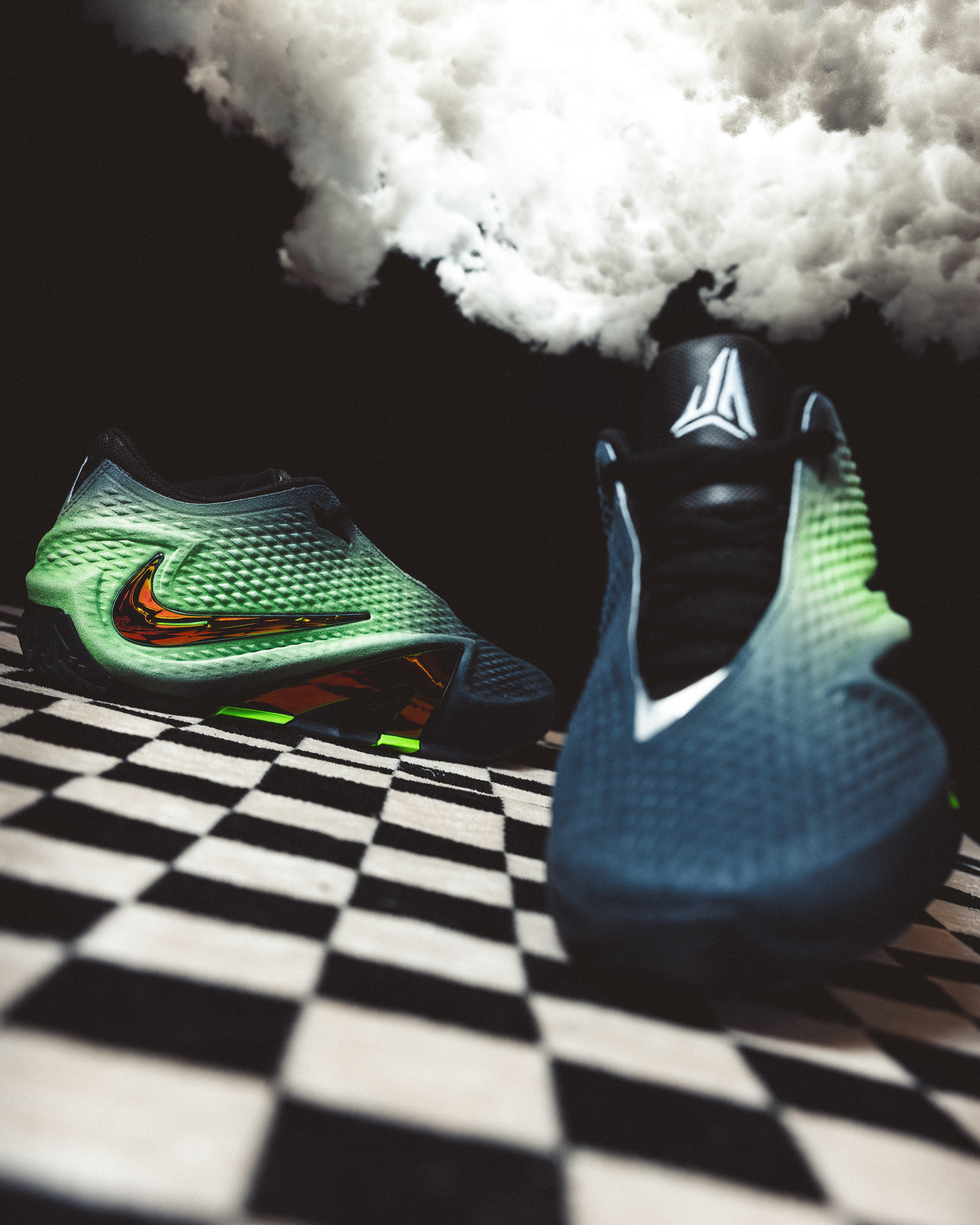 Nike Ja 4 Nightmare basketball shoes displayed on a black-and-white checkered surface with green textured uppers, black toe details, iridescent Swooshes and white smoke in the background.