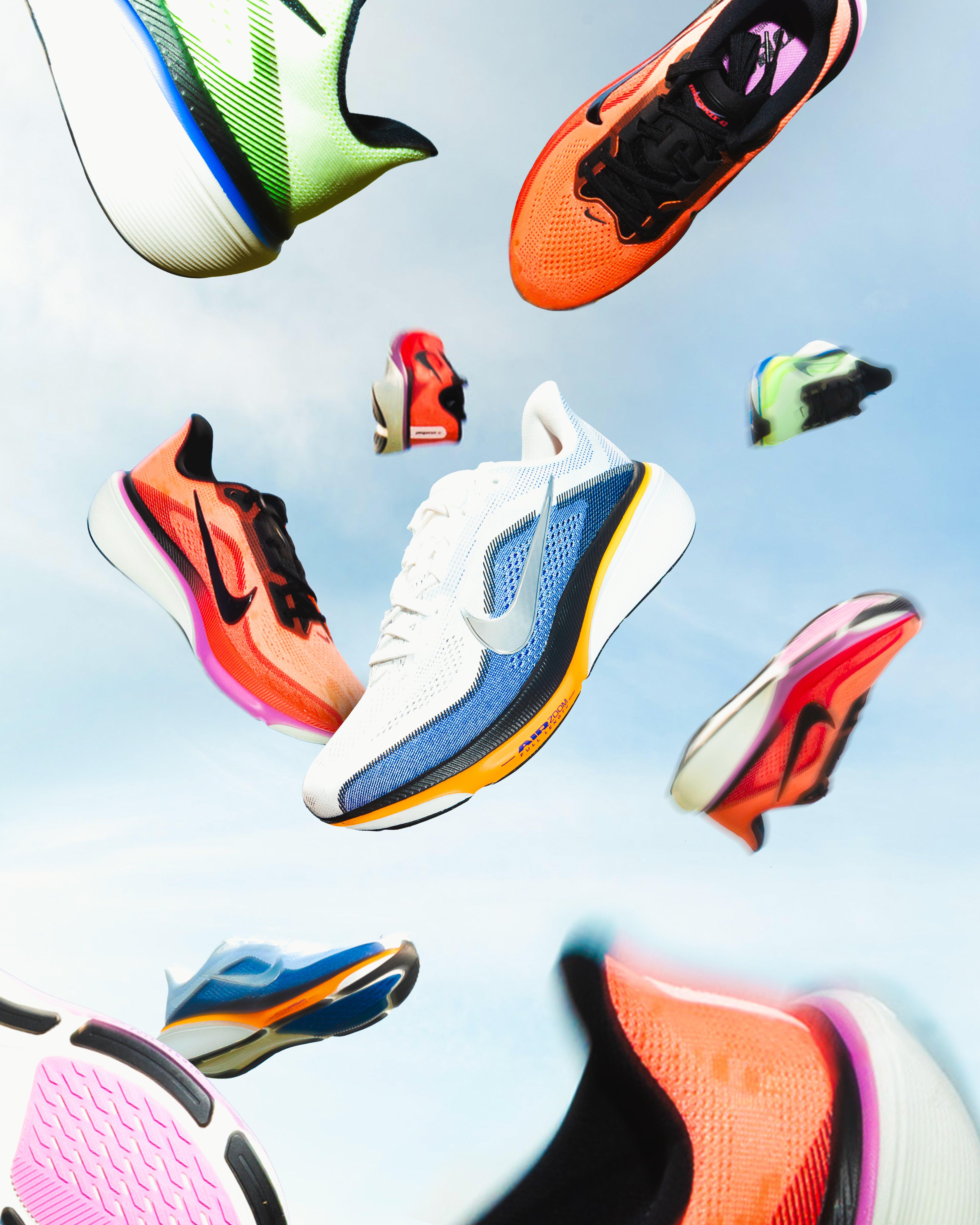 Multiple Nike Pegasus 42 running shoes in bright colorways appear suspended midair against a blue sky, highlighting the shoe&rsquo;s lightweight design and cushioning.