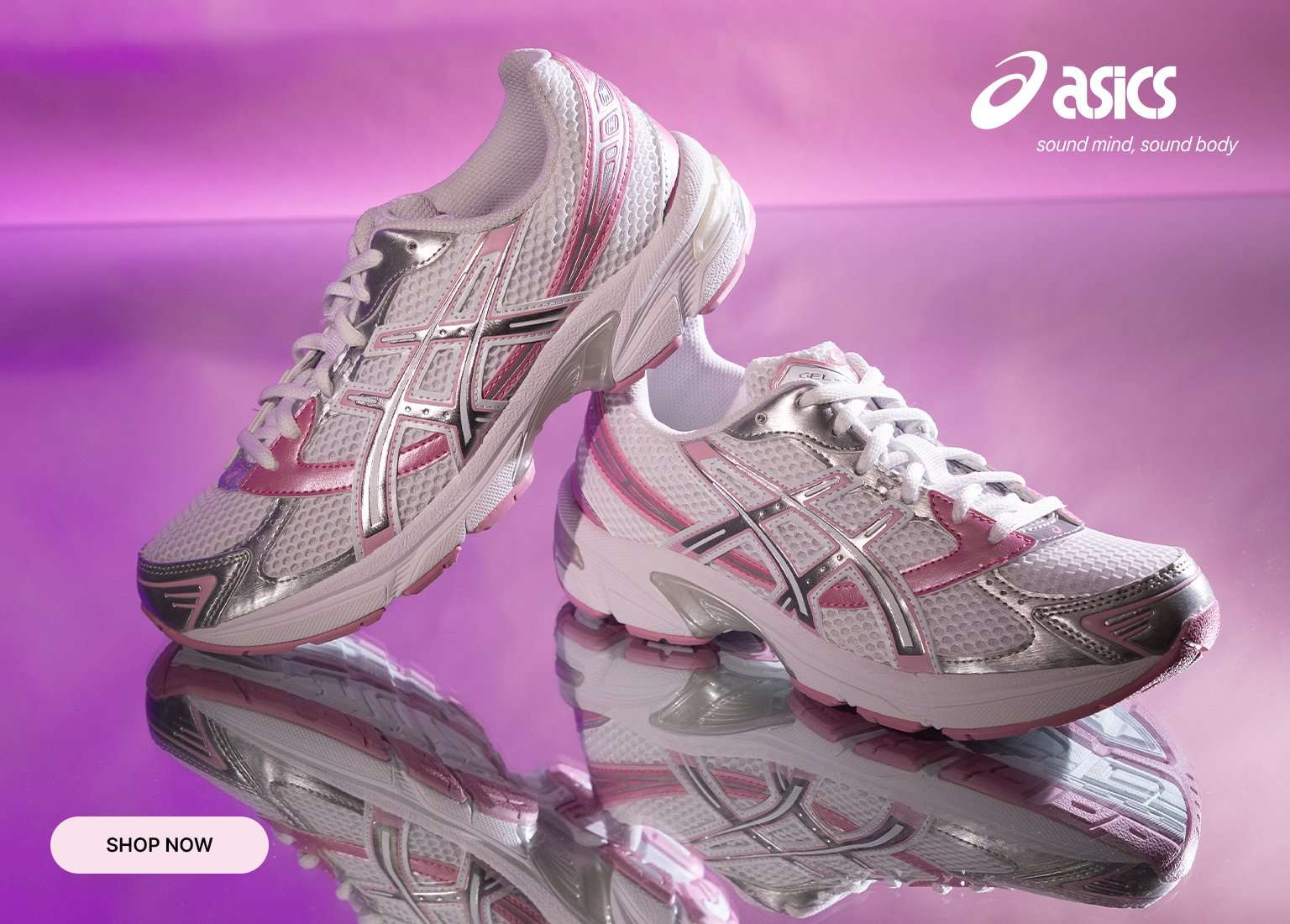 Pair of white and pink ASICS running shoes with silver metallic accents, displayed on a reflective surface against a purple background.