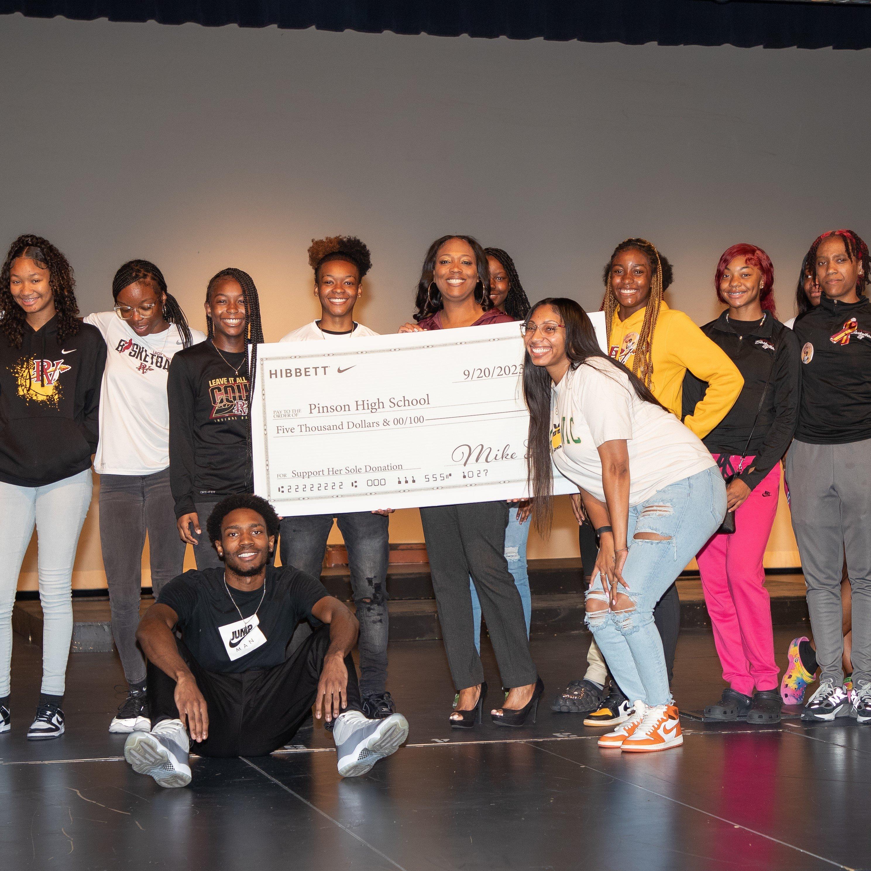 Group image of Pinson Valley HS Girls' basketball team and Hibbett reps with donation check