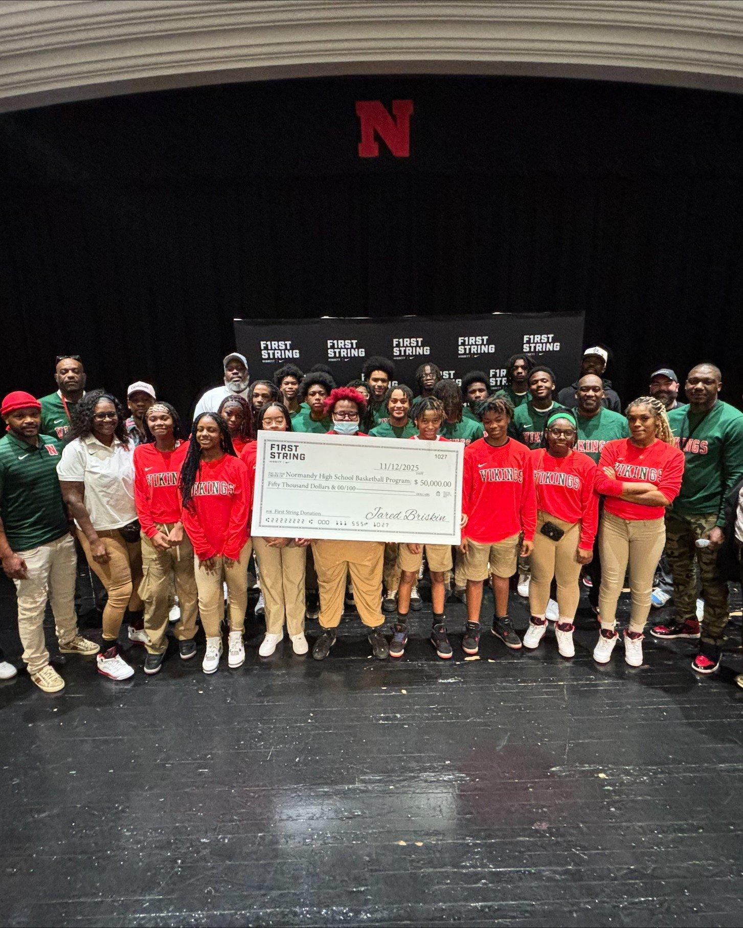 Normandy High School boys' and girls' basketball teams posing on stage with a large ceremonial check for $50,000 from the Hibbett and Nike First String program.