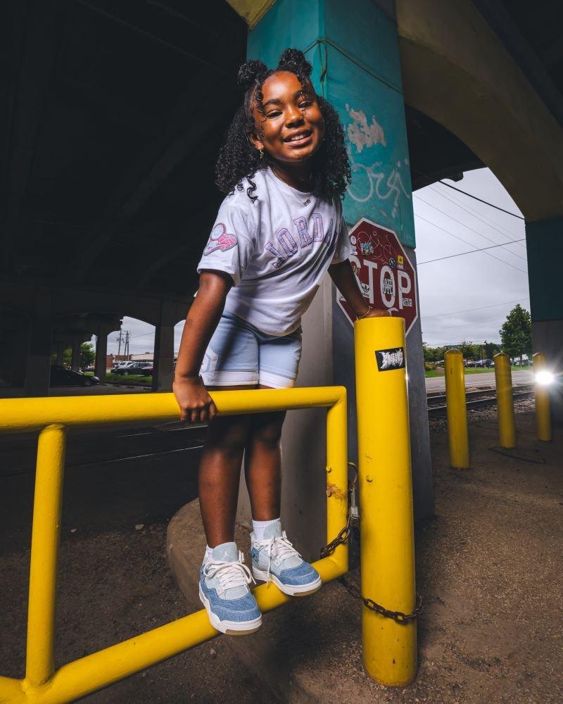 Girl modeling Jordan 4 Retro "Worn Blue" Girls' Shoe