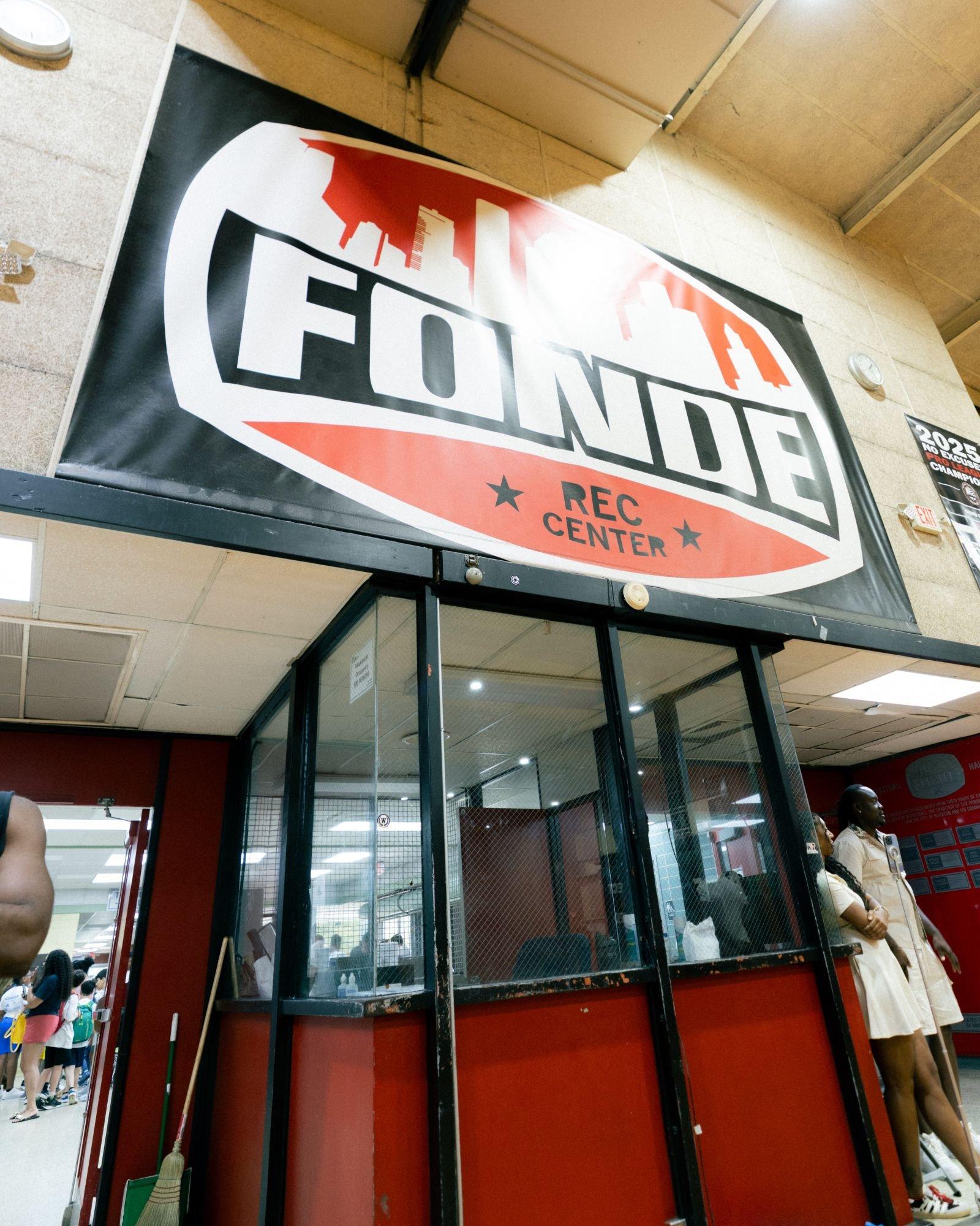 Fond&eacute; Recreation Center entrance featuring a large overhead Fond&eacute; sign inside the gym, with attendees gathered near the facility entrance during a community basketball event.