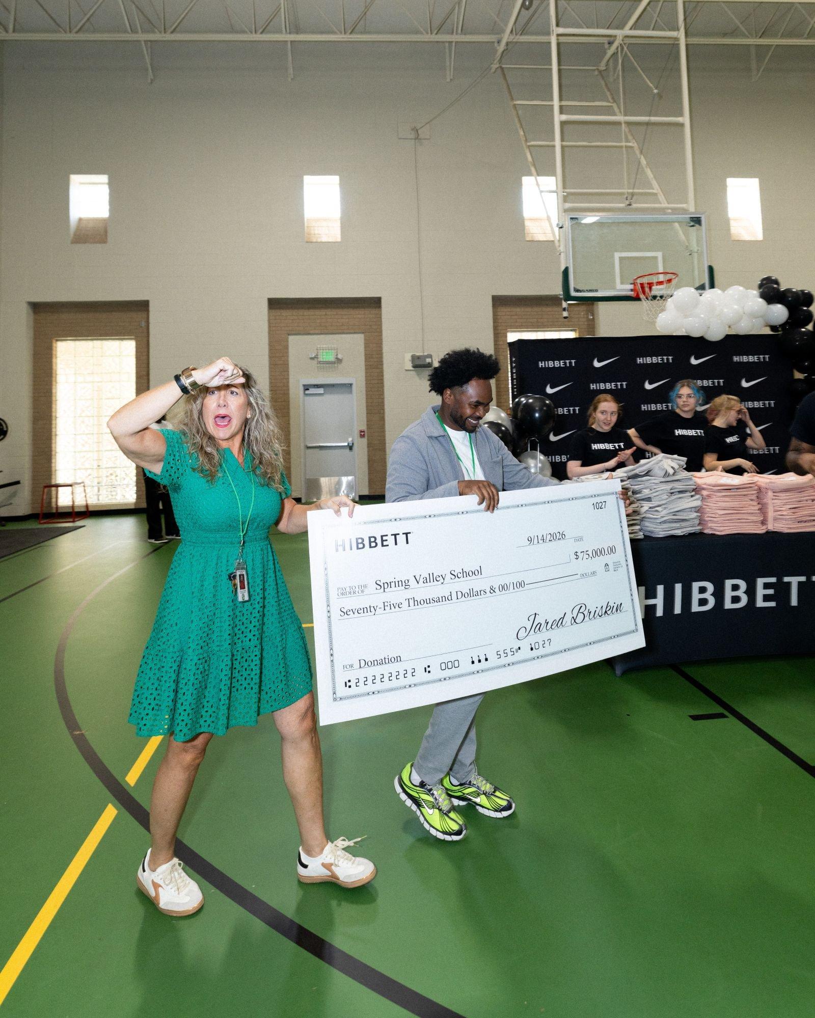 Hibbett presents a $75,000 donation check to Spring Valley School during a school celebration event in Birmingham.