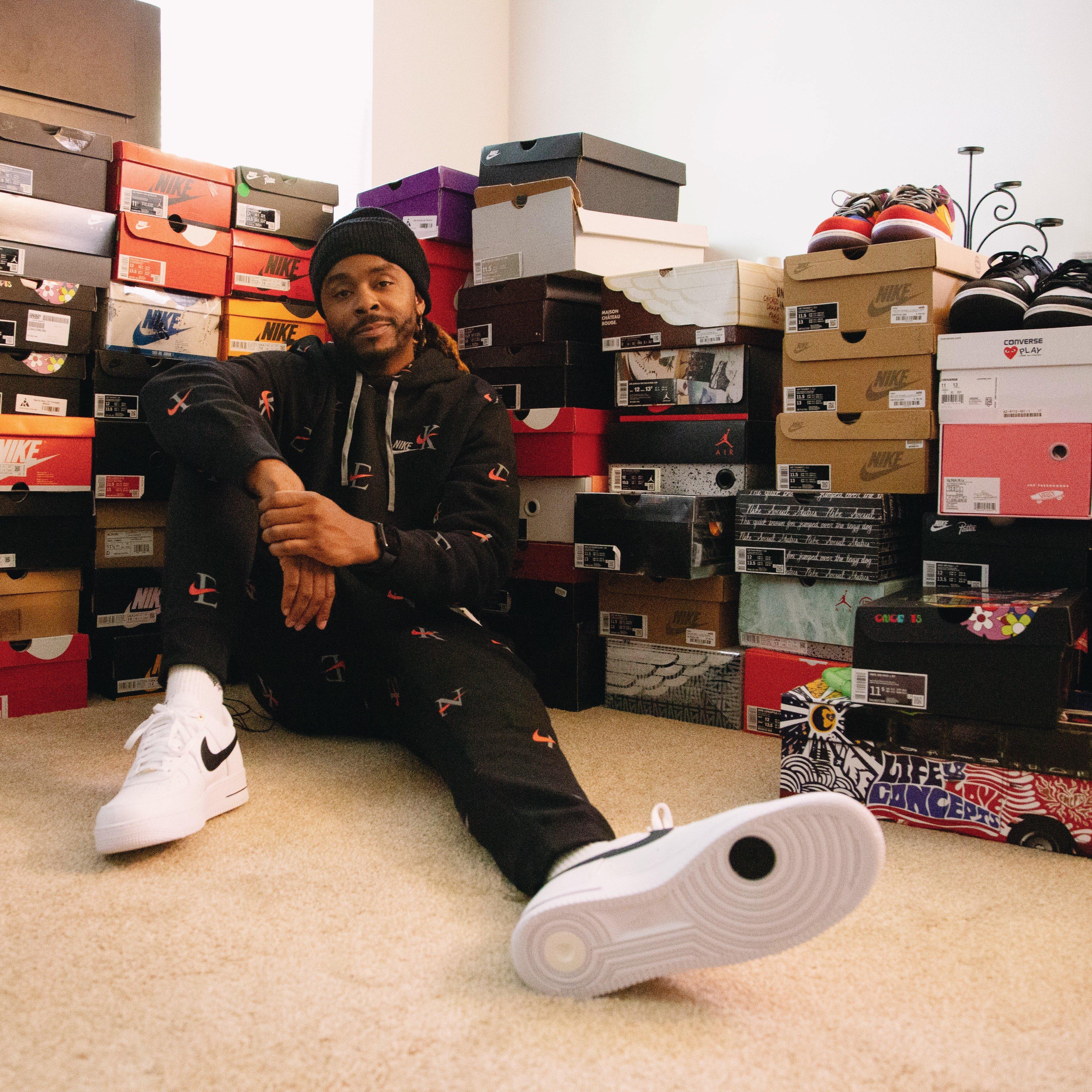 Derek Wilson seated in front of his sneaker collection