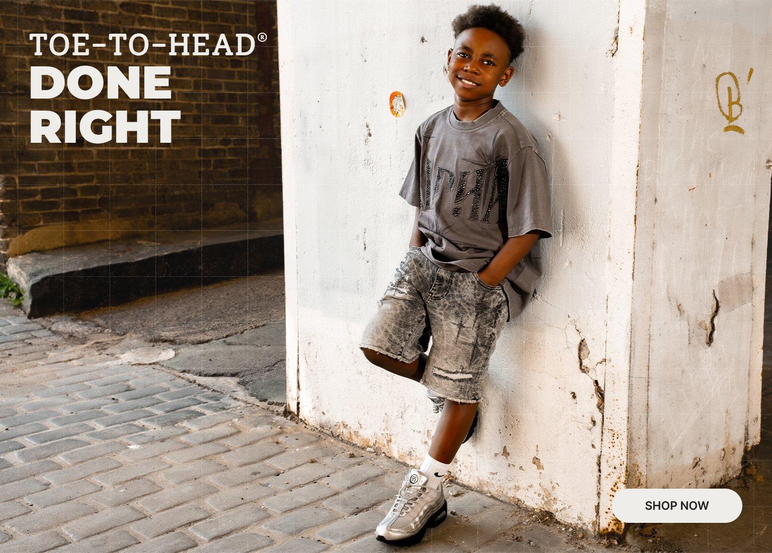 Promotional Hibbett banner featuring a child wearing a graphic T-shirt, denim shorts, crew socks, and athletic sneakers in an urban setting. The image includes the text “Toe-to-Head Done Right” and a “Shop Now” call-to-action, highlighting complete back-to-school apparel and footwear looks from Hibbett.