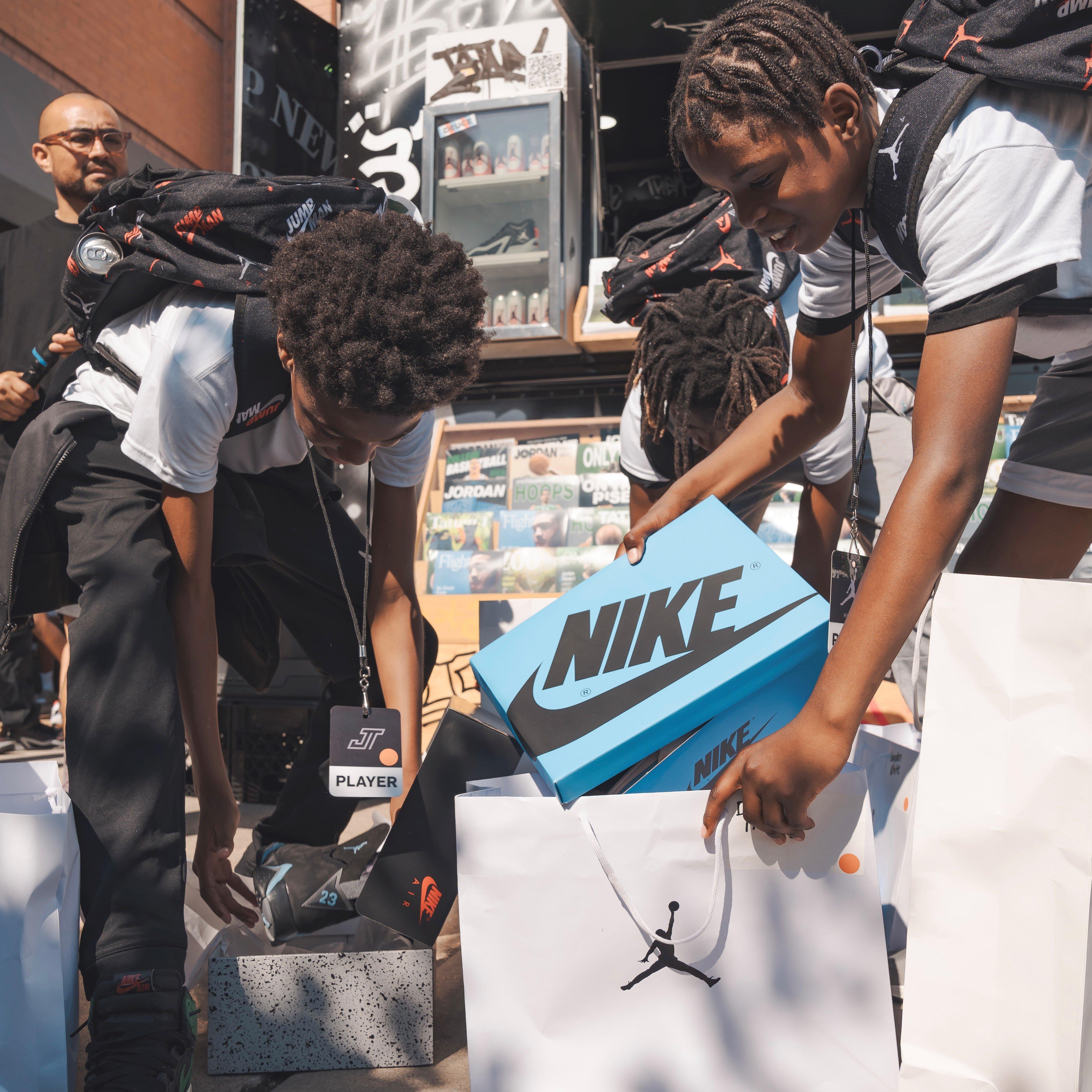 Kids pulling a shoe box from a Jordan-branded shopping bag