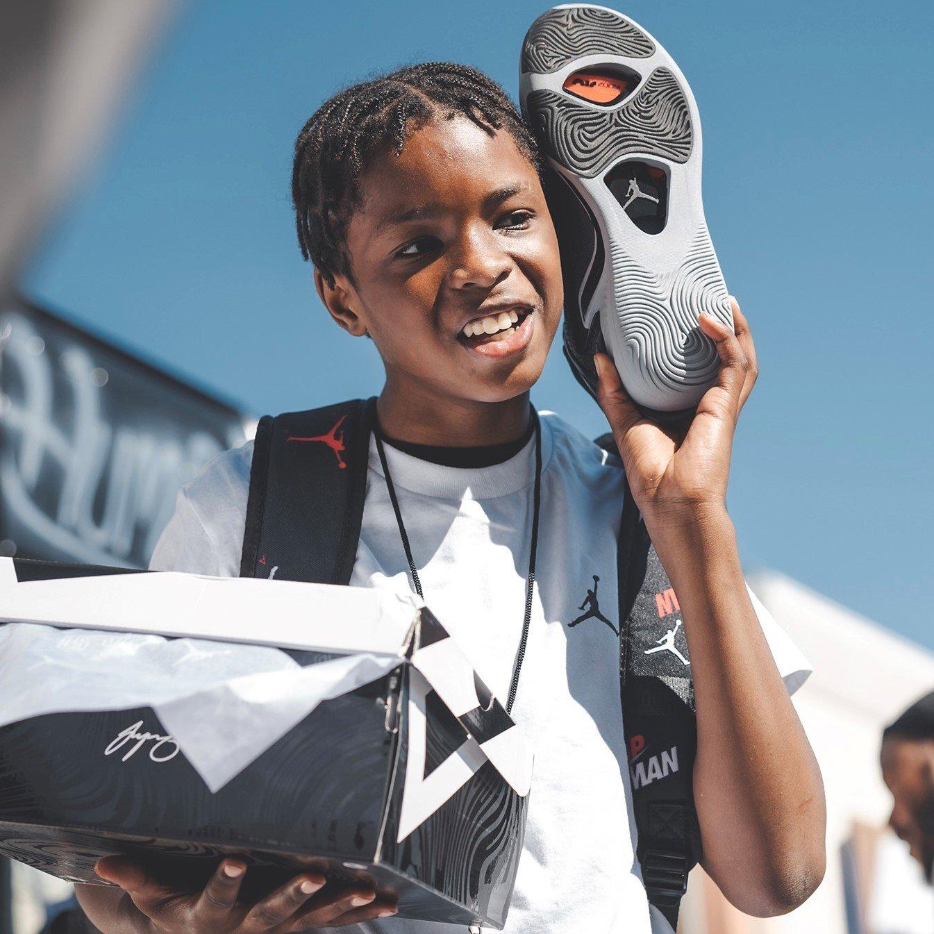 Kid holding up a Jayson Tatum 1 sneaker up near his face showing it off