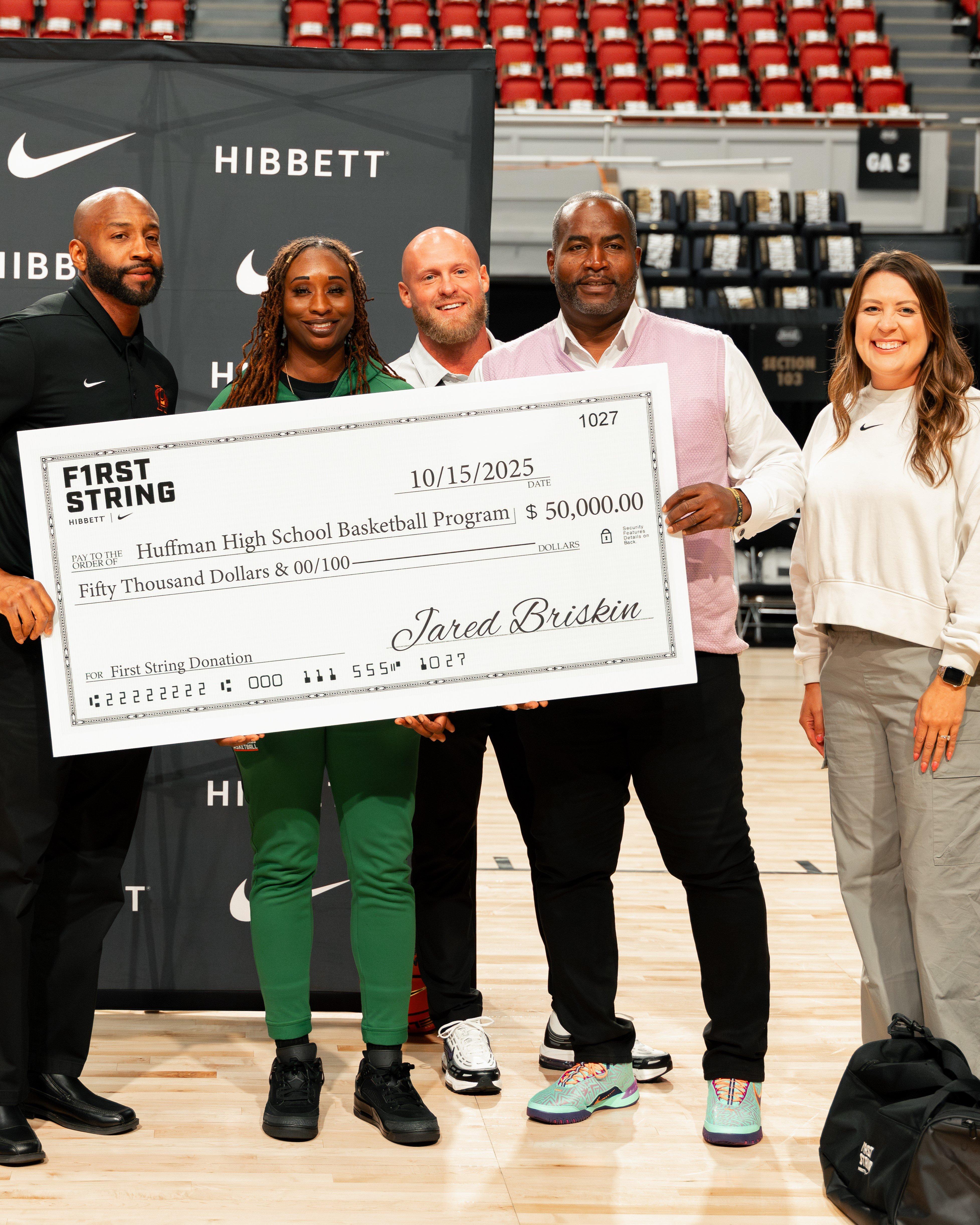 A group photo of the Huffman High School Girls Basketball team and their coaches, standing on the court in matching green tracksuits while holding basketballs.