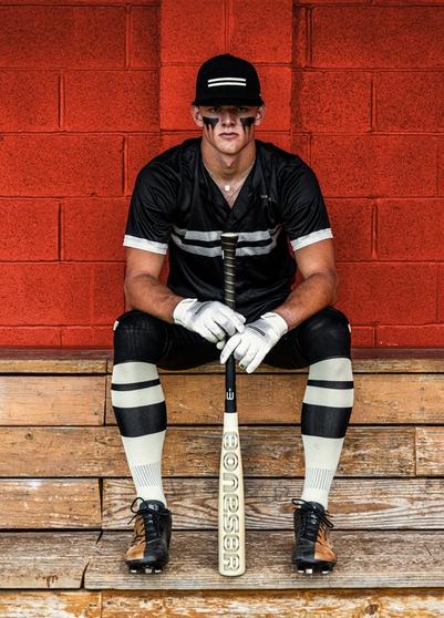 Teen male baseball player posing in dugout with Warstic Bonesaber baseball bat