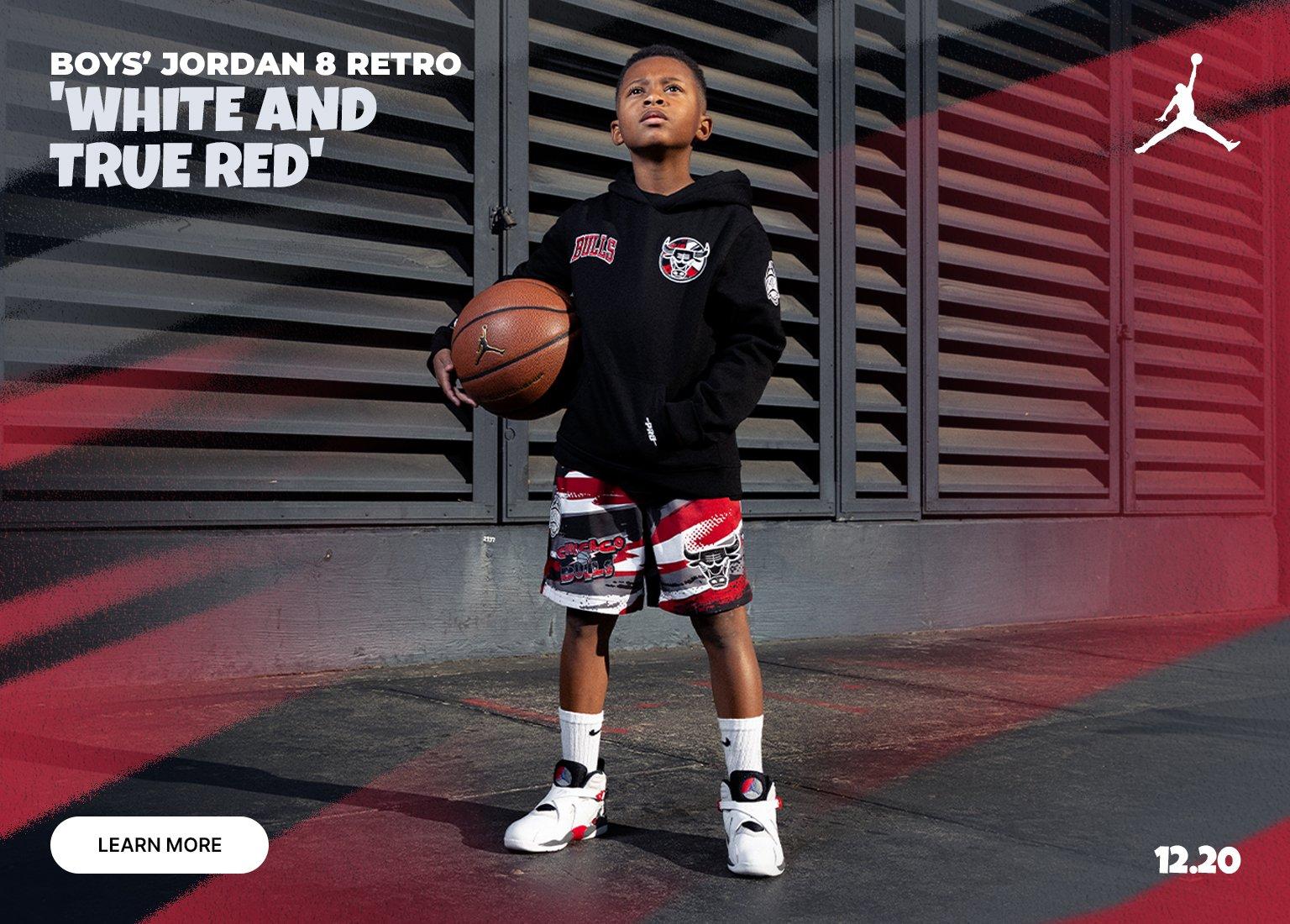 Boys’ Jordan 8 Retro “White and True Red” sneakers worn by a kid holding a basketball, launching December 20.