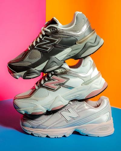 New Balance Y2K-inspired sneakers in silver, white, and black stacked against a pink, orange, and blue background.