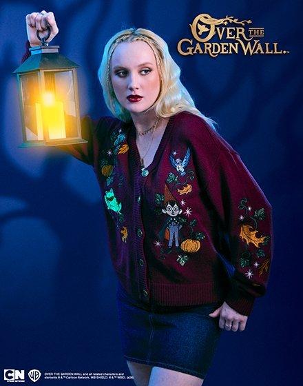 Woman holding a lantern, wearing an Over the Garden Wall embroidered cardigan and denim skirt. Shop Now.