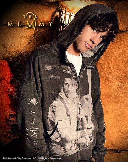 Man wearing a hooded zip-up sweatshirt with “The Mummy” graphic and text on the sleeve. Shop Now.