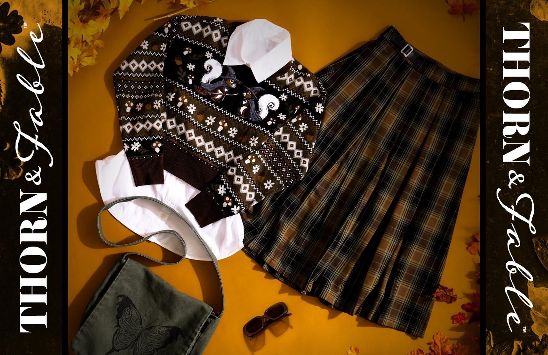 Thorntale & Fable sweater layered over white shirt with plaid skirt, bag and sunglasses. Shop Now.