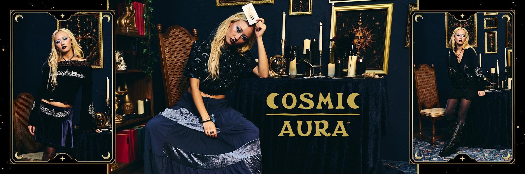 Model in dark celestial outfit holding a tarot card beside a table with “COSMIC AURA” text. Shop Now.