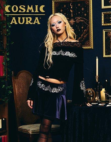 Model wearing a black off-shoulder top and skirt with silver designs. Shop Now.