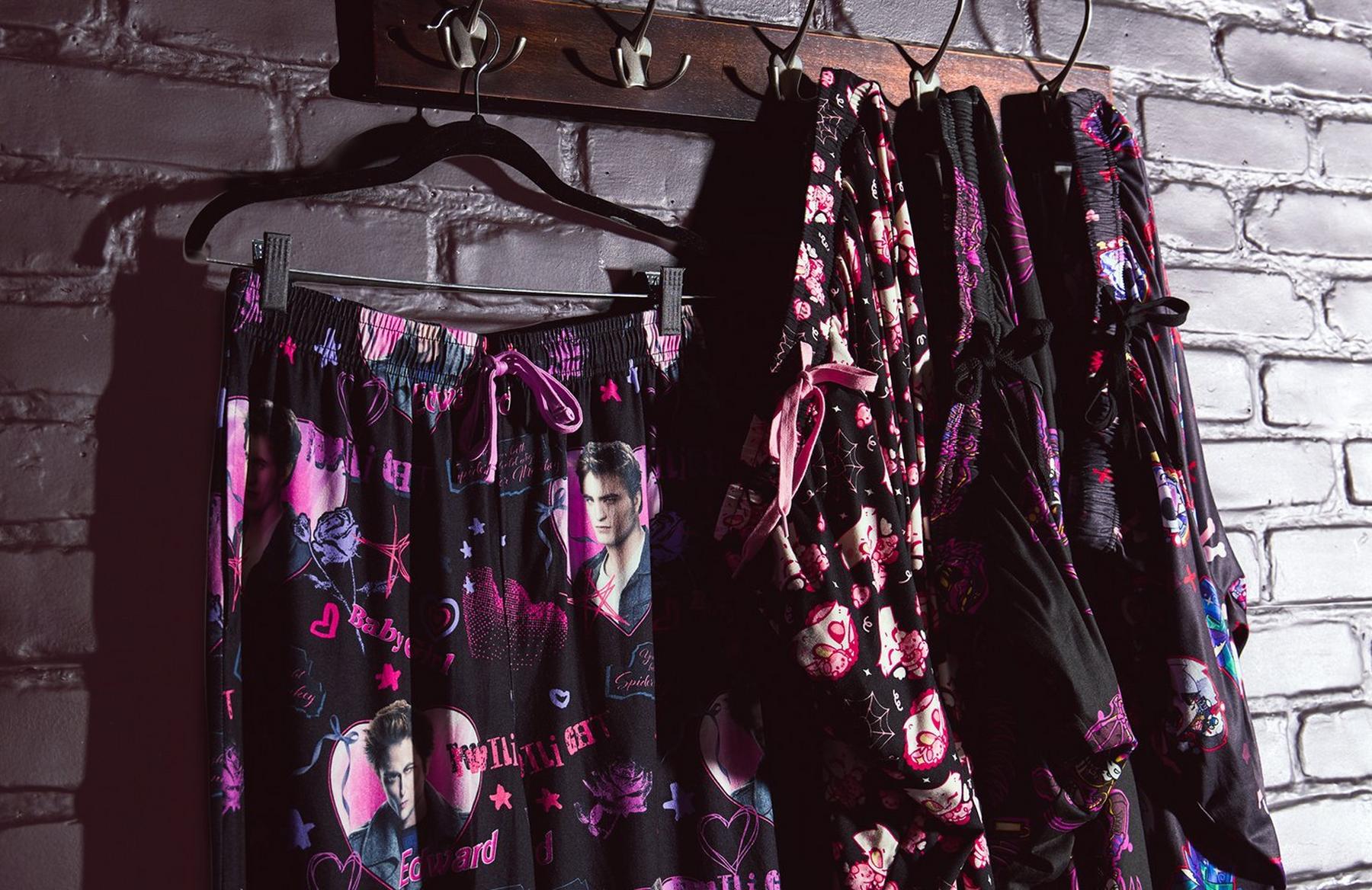 Printed pajama pants and matching robes hanging on hooks. Shop Now.