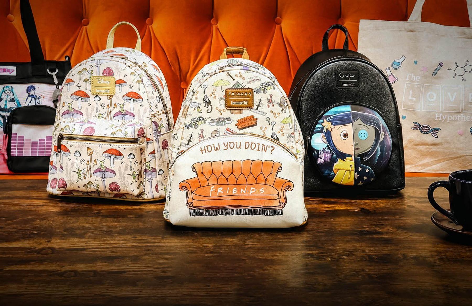 Three Loungefly mini backpacks with Disney, Friends, and Coraline designs on a table. Shop Now.