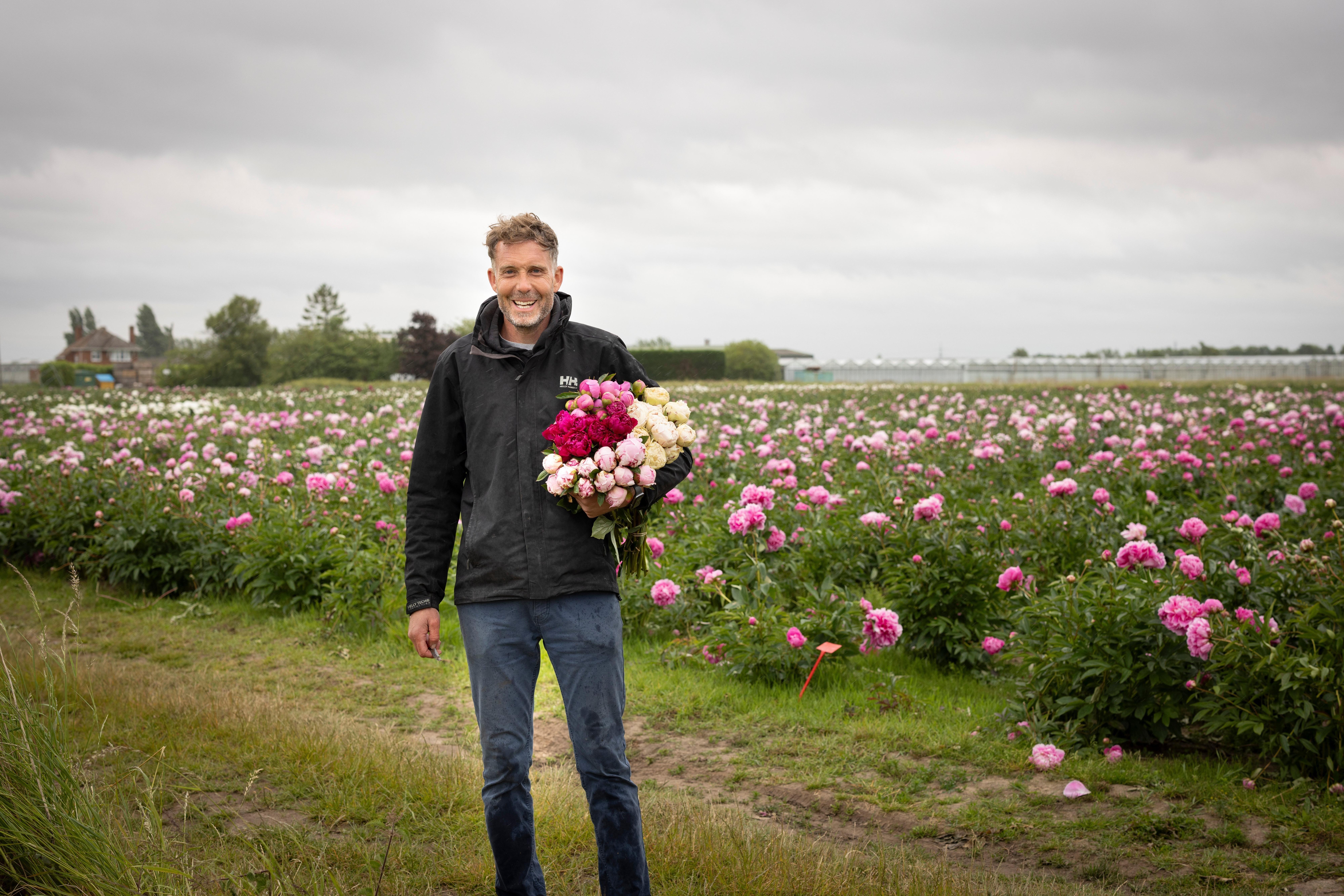 A British flower grower carrying a bunch of freshly cut stems through the field