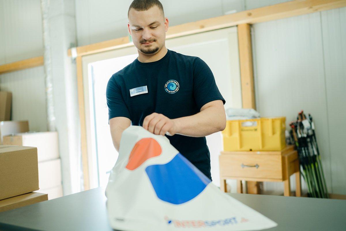 Ein Mensch steht in einem Lager und packt ein Paket zusammen.