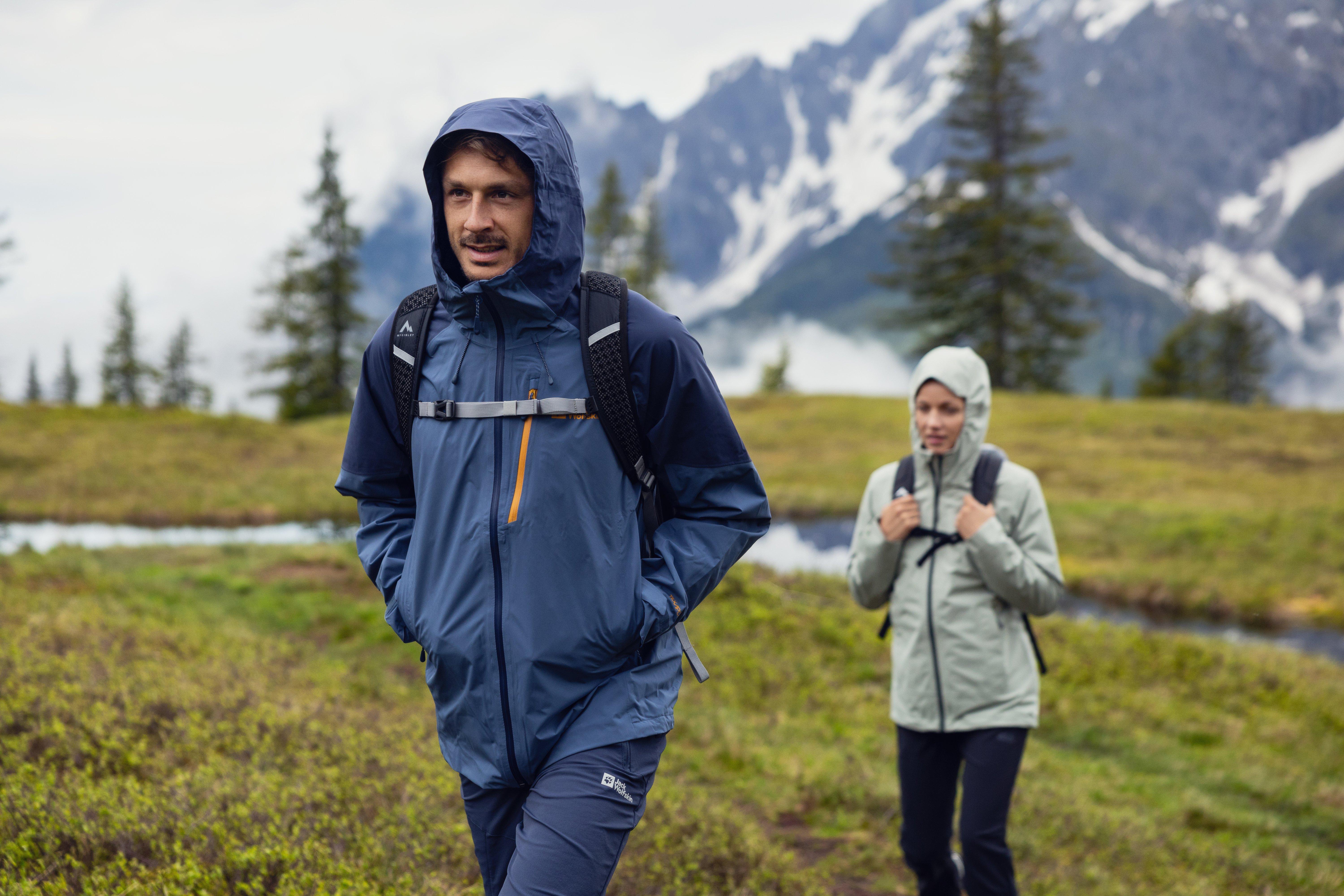 ein Mann und eine Frau wandern im Regen im Hintergrund Berge