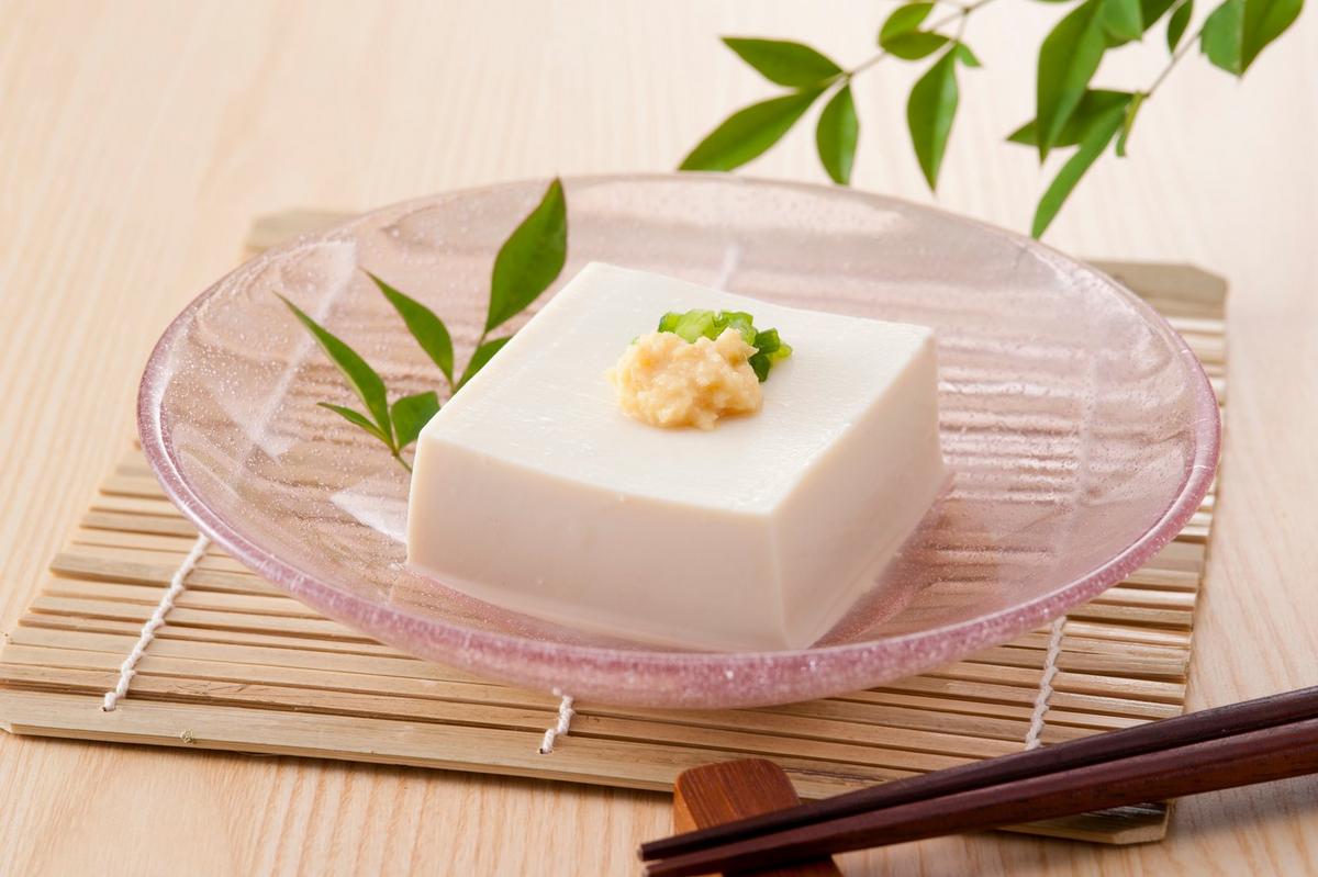 Hiyayakko chilled tofu presented in a glass bowl on a wooden table
