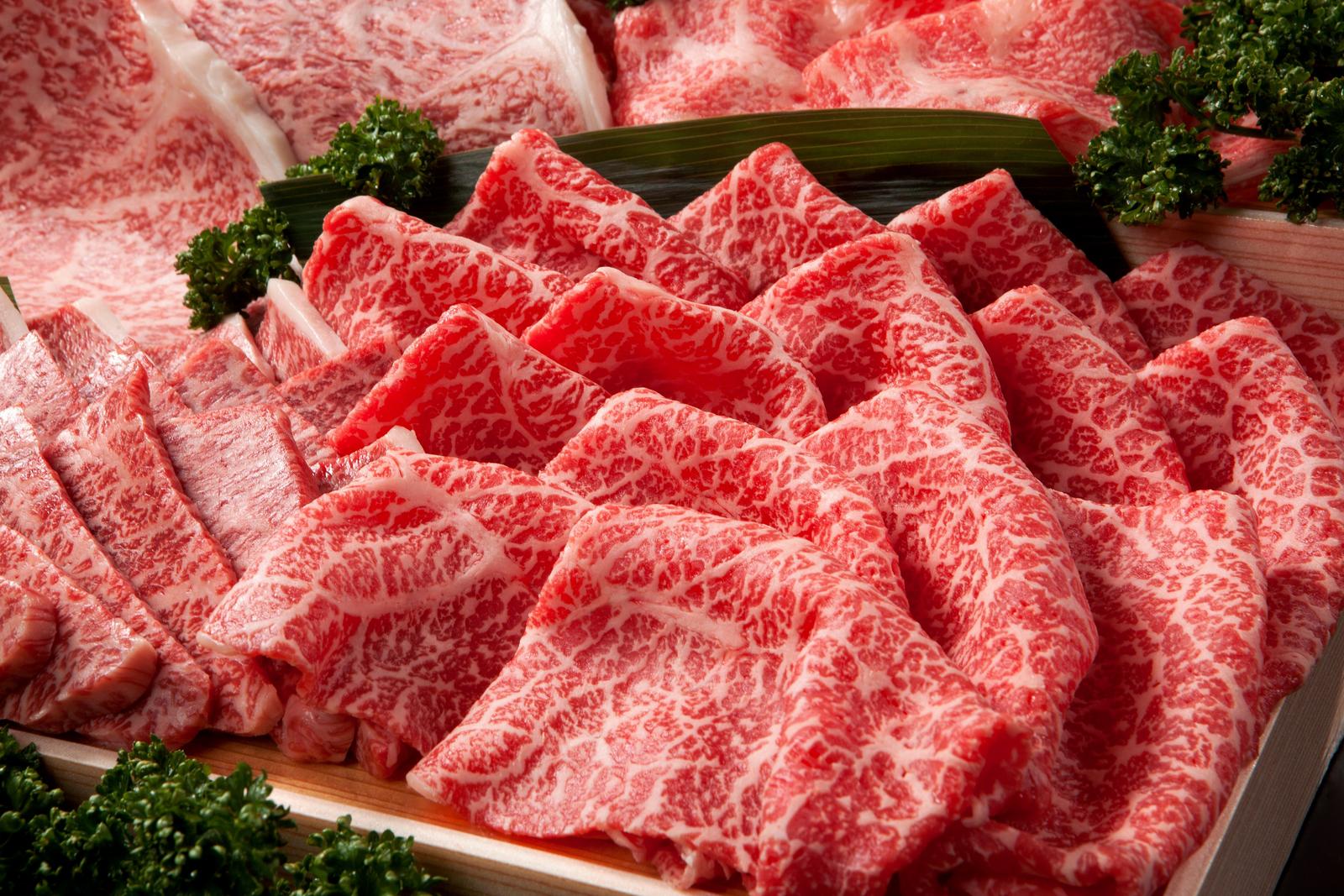 Thinly sliced meat placed on a black ceramic plate