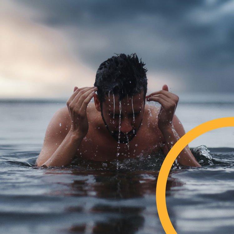 An image of a man swimming outdoors who has just broken the surface of the water.