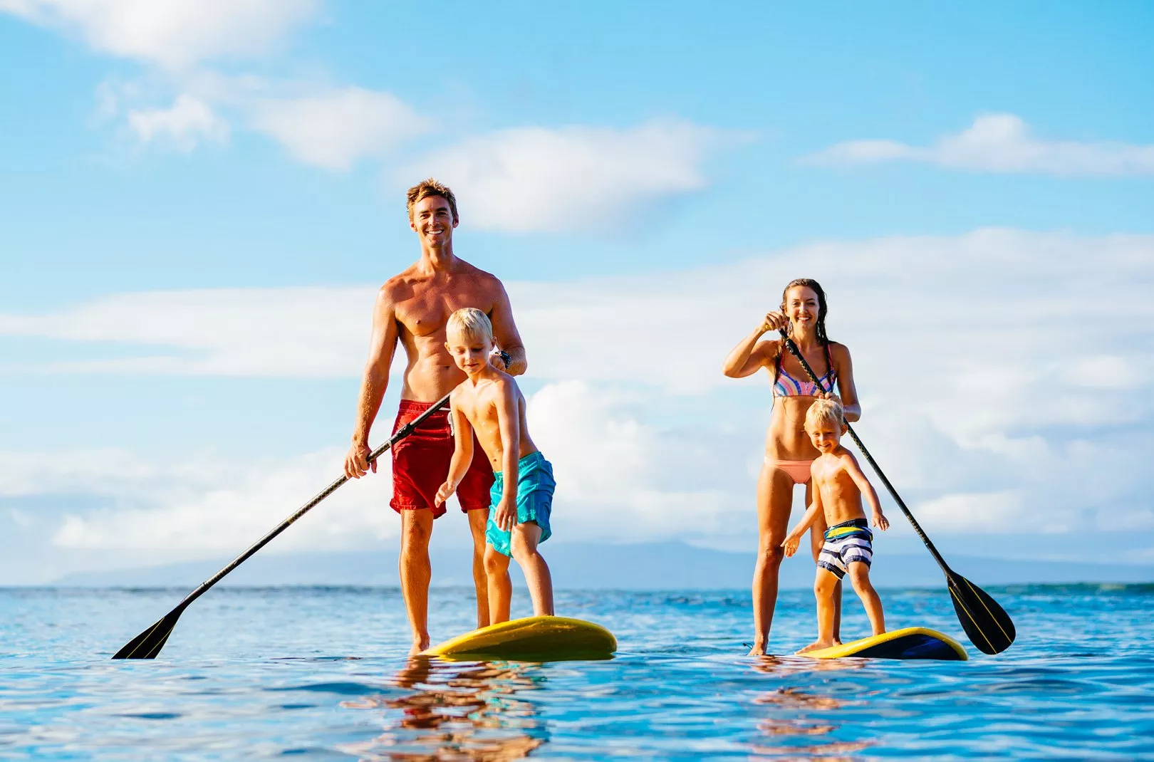 family stand-up paddleboarding in the sea
