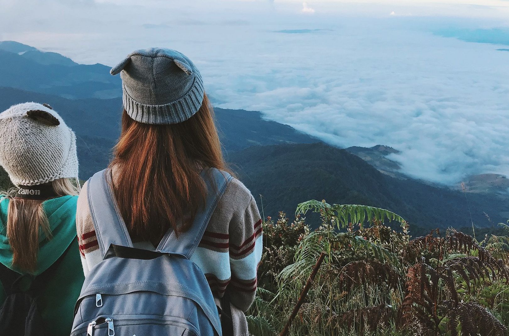 Two people at the top of a hill looking over the clouds