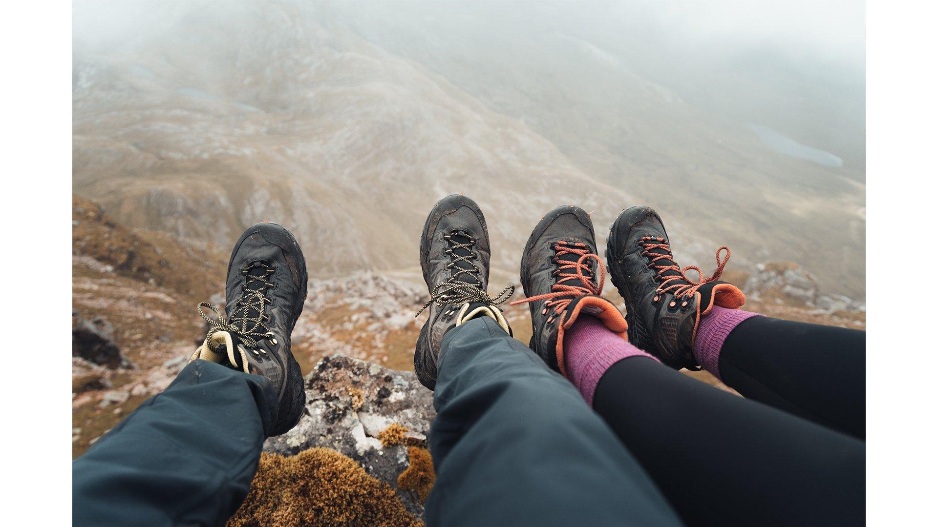 A couple dangling their feet off a rock near the summit of a Scottish mountain while wearing the Scarpa Rush Trk LT Boots
