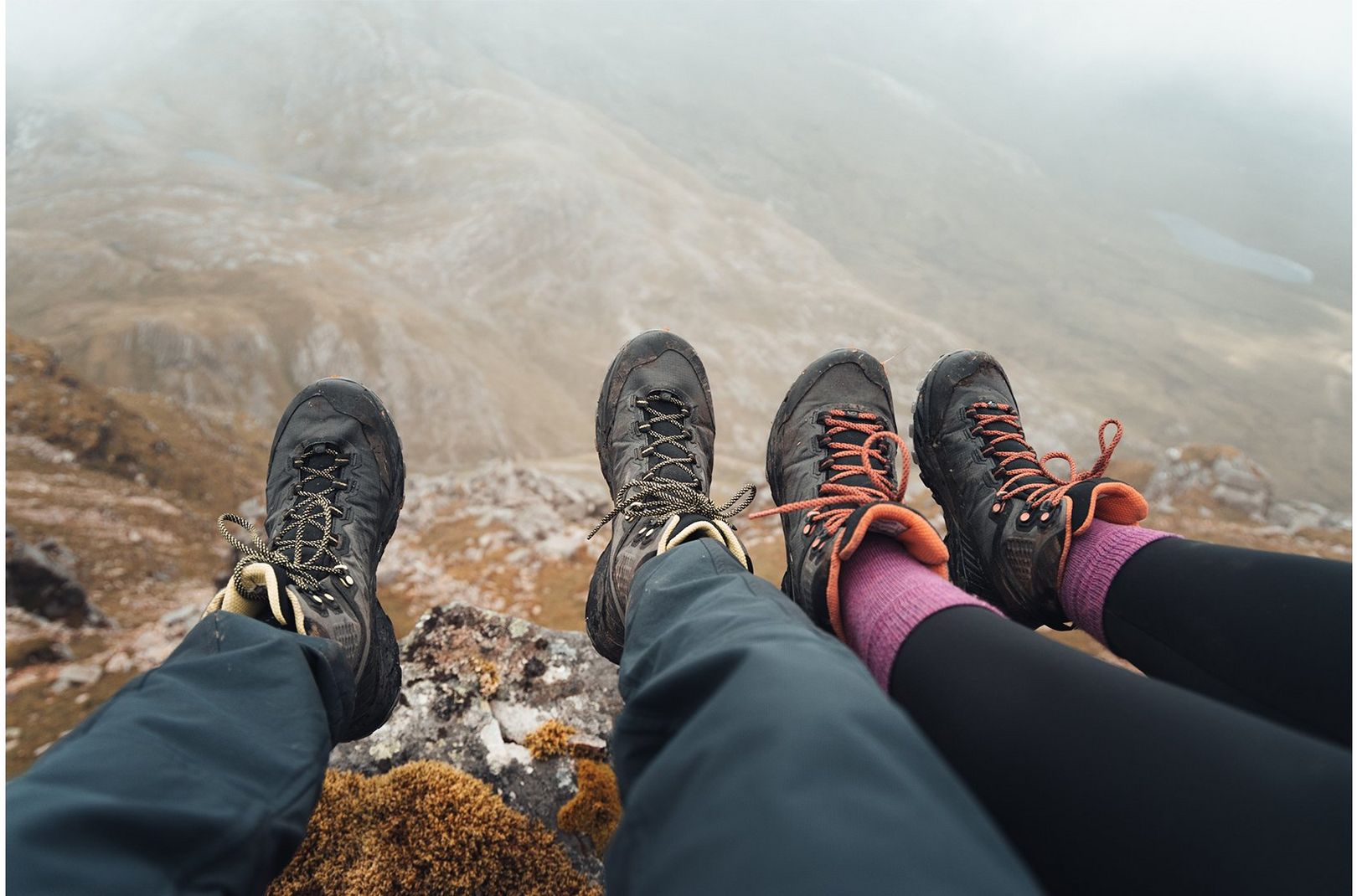 A couple dangling their feet off a rock near the summit of a Scottish mountain while wearing the Scarpa Rush Trk LT Boots