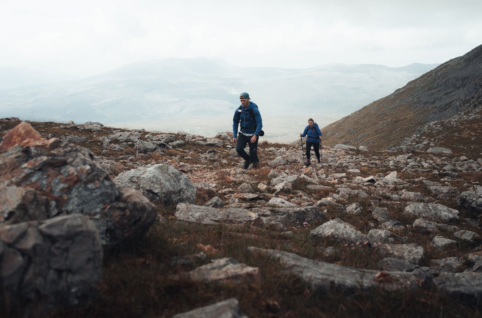 A couple hiking up a rocky mountain path in Scotland