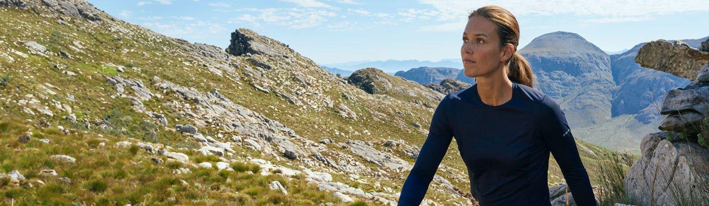 Woman hiking in the sunny mountains wearing longsleeve baselayer