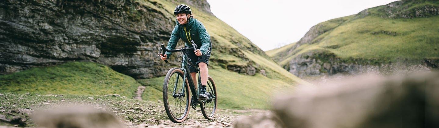 Woman riding eBike through a valley with hills either side
