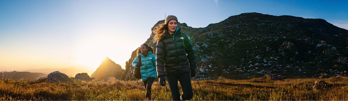 Two people hillkwalking wearing down jackets