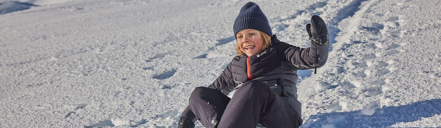 Kid sledging down a ski slope