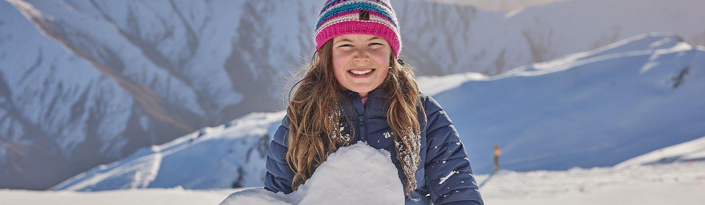 Kid making a snowman on the ski slope
