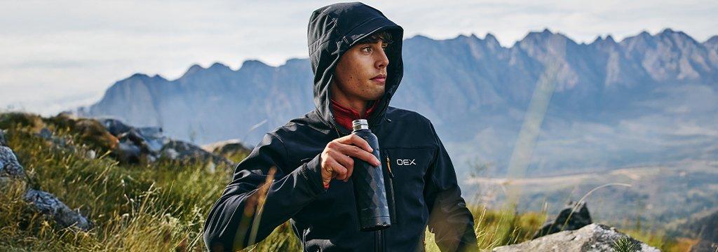 Person wearing a softshell jacket in the mountains with hood up