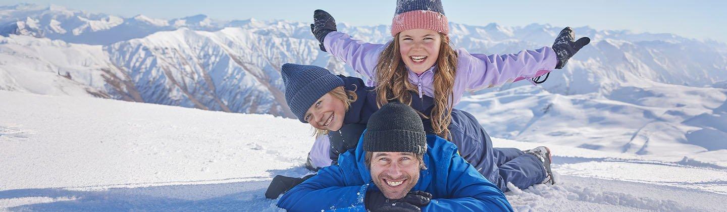 A family wearing ski gear and playing in the snow