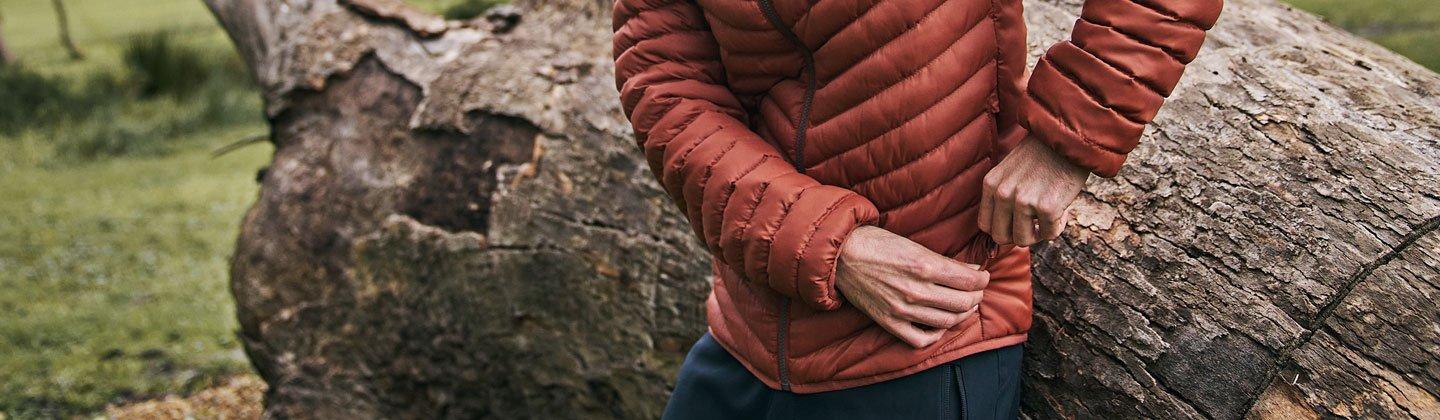 Closeup of a person wearing a down jacket and zipping up the pocket