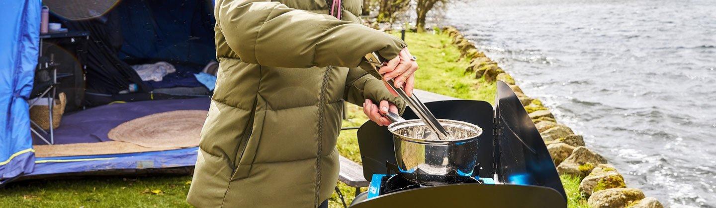 A person cooking on a camping grill