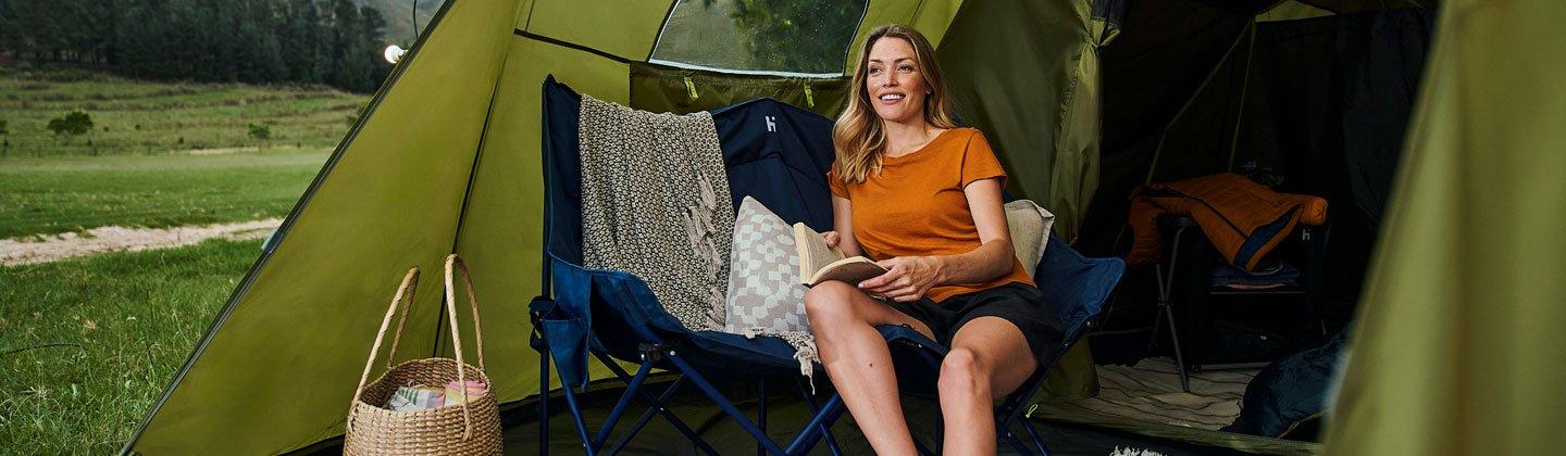 Person reading a book inside a tent porch