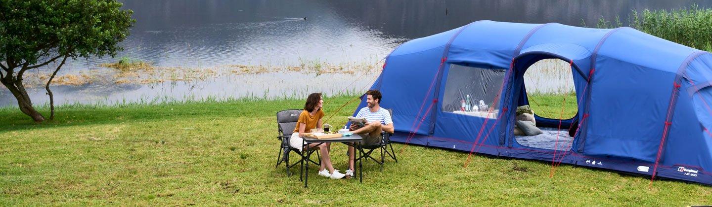 A couple having dinner outside of their inflatable tent