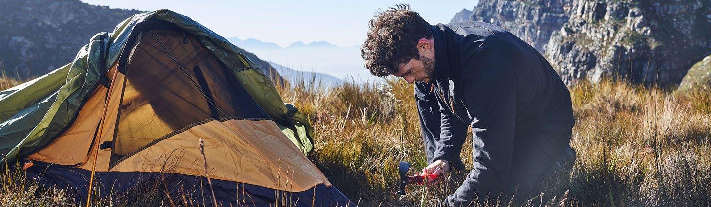 Person pegging a backpacking tent down high up in the mountains