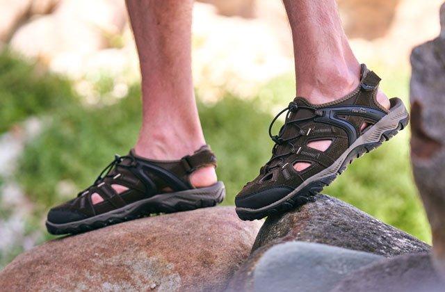 Closeup of a person walking over rocks in a pair of sandals